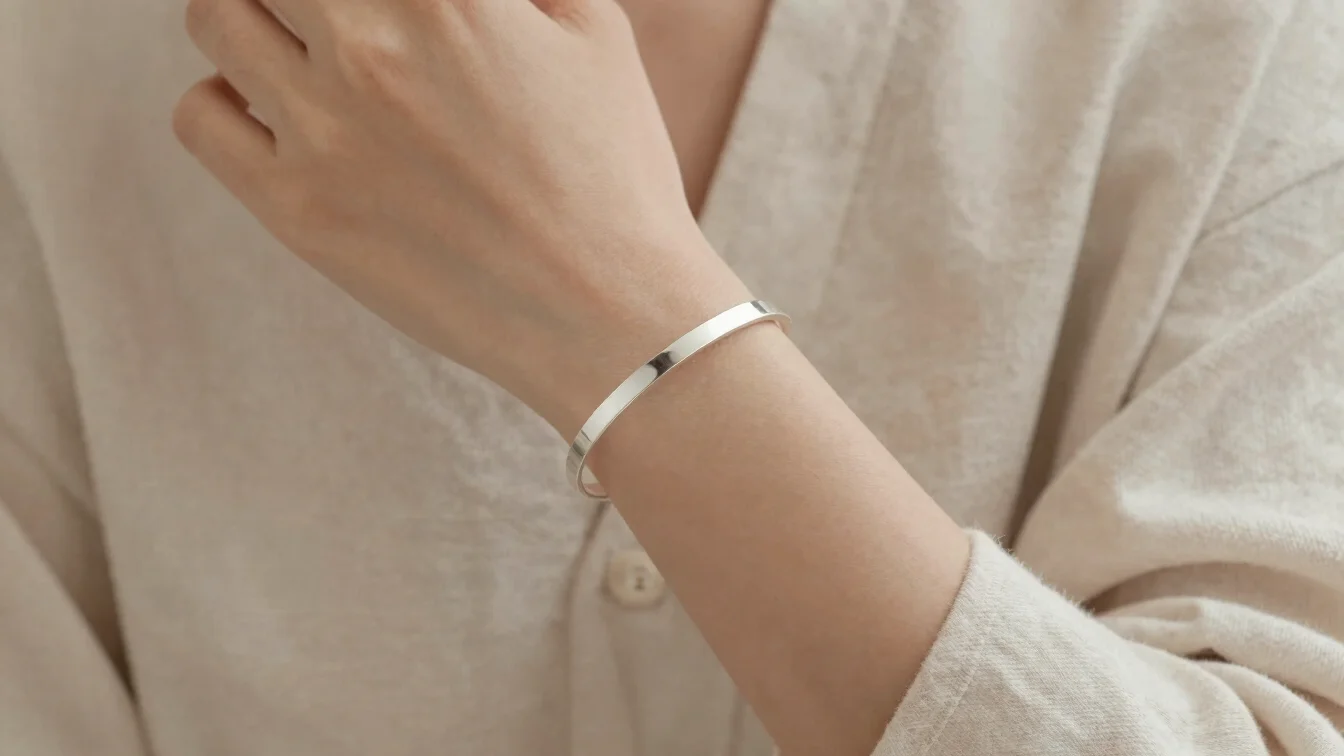 Close-up shot of a minimalist silver bracelet worn by a person in