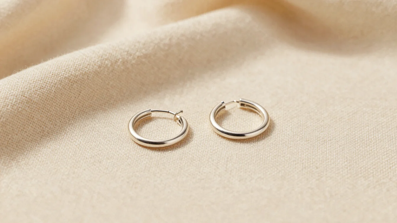 Close-up shot of small silver hoop earrings on a cream linen back